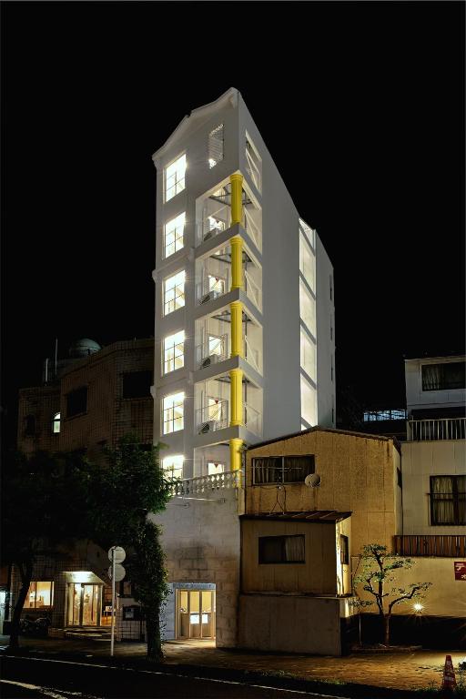a tall white building at night in a city at Hotel URO in Nagasaki