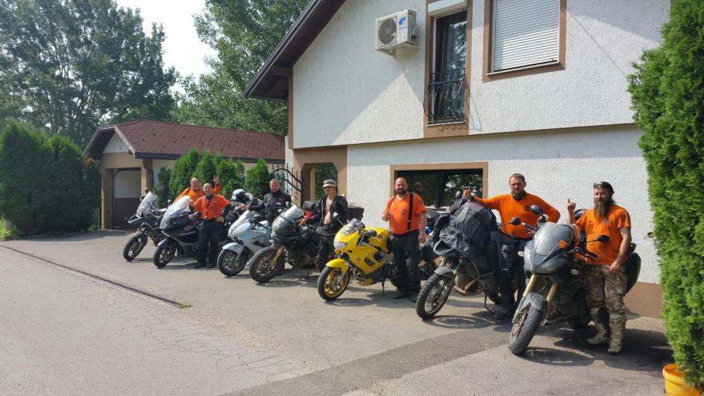 a group of people in orange shirts standing next to their motorcycles at Guest House Majstorovic in Banja Luka