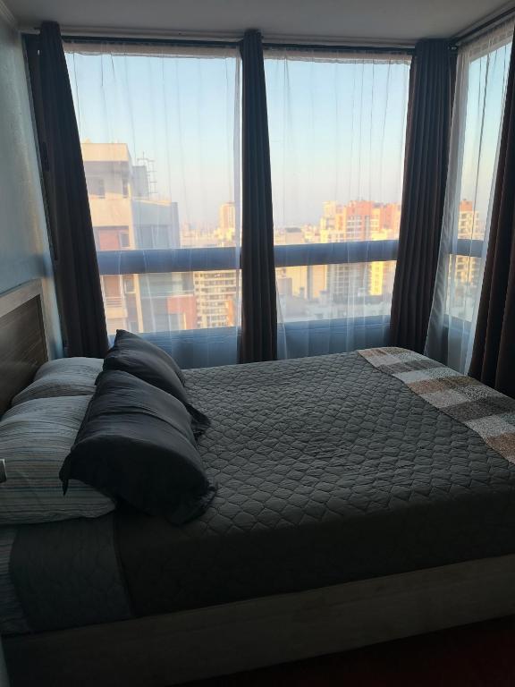 a bedroom with a bed with pillows and a large window at Never Give Up Suites in Santiago