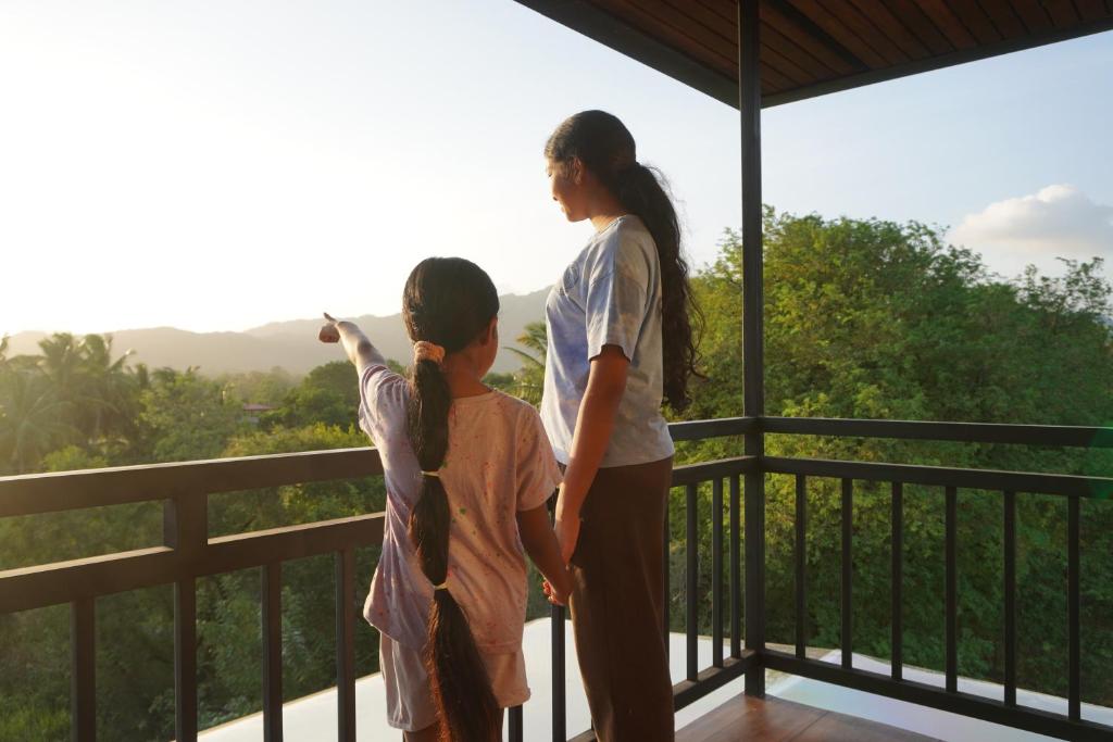 zwei Mädchen stehen auf einem Balkon und schauen in die Aussicht in der Unterkunft Green Earth Resort in Dambulla