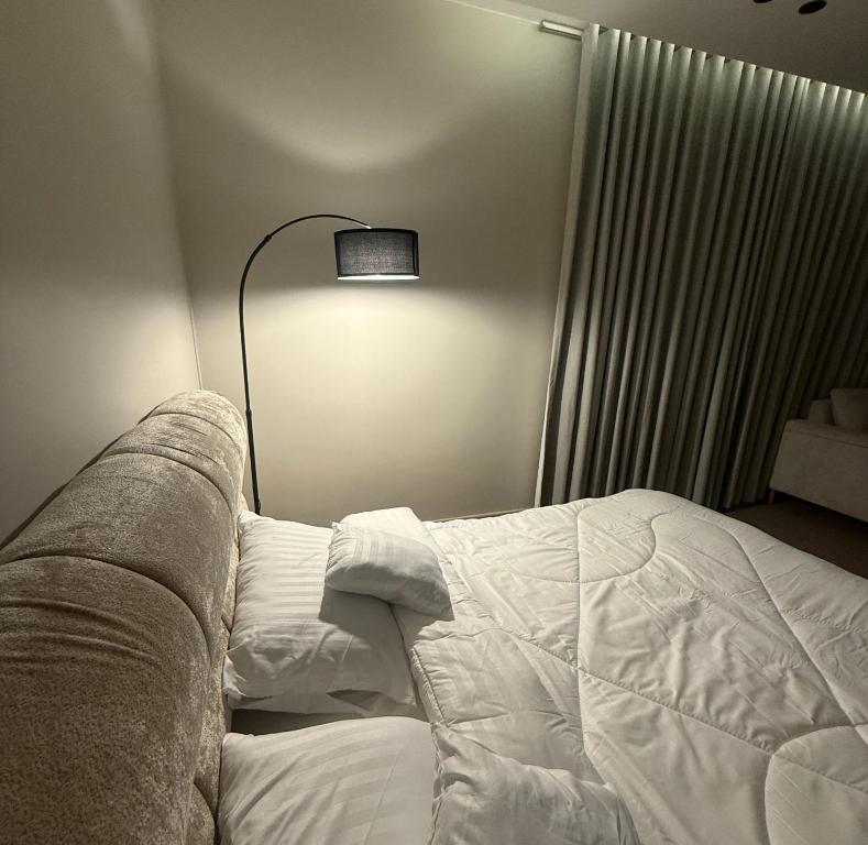 a bedroom with a white bed and a lamp at استديو الهدوء in Dammam