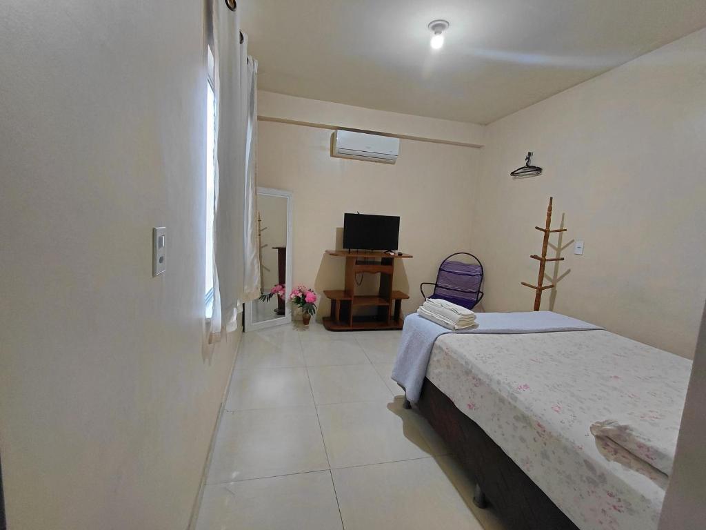 a bedroom with a bed and a desk and a television at Casa da Deusa in Belém