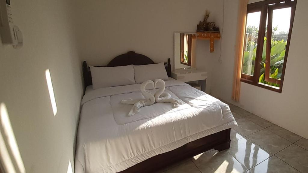 タバナンにあるThe Carik Homestayのベッドルーム1室(白いリボンのベッド1台付)