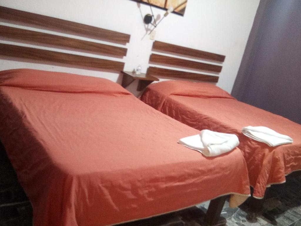 Dos camas en una habitación con sábanas rojas y zapatillas blancas. en Hotel Viña del Mar, en Lázaro Cárdenas