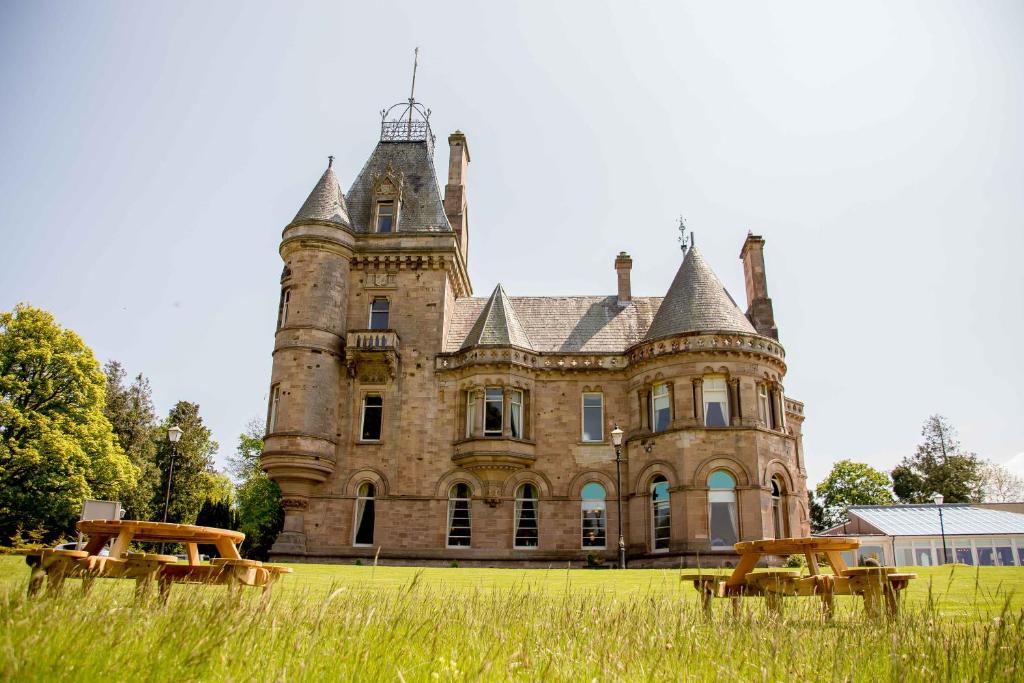 an old castle with benches in front of it at Cornhill Castle in Biggar
