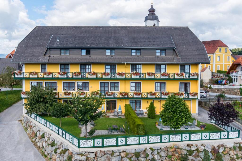 duży żółty budynek z czarnym dachem w obiekcie Florianihof w mieście Miesenbach