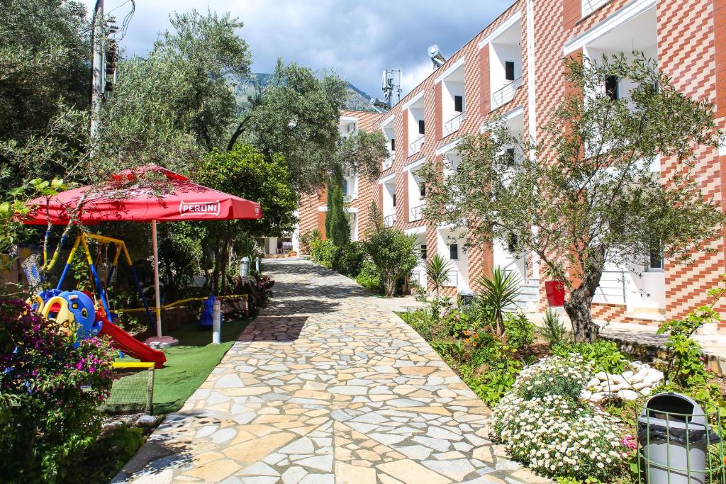a garden with a playground and an umbrella at Noan Hotel & Resort in Dhërmi