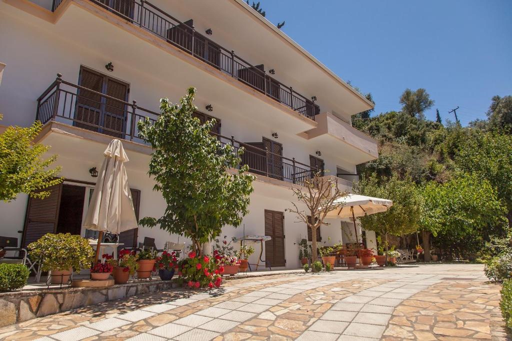 a large white building with plants and an umbrella at Captain's Studios in Vasiliki