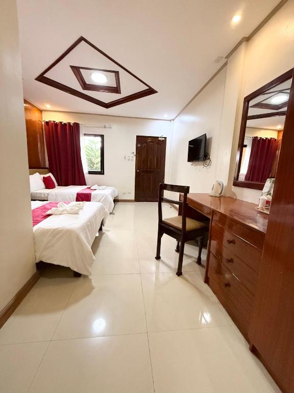 a bedroom with two beds and a desk with a mirror at Mariafe Inn in Puerto Princesa City