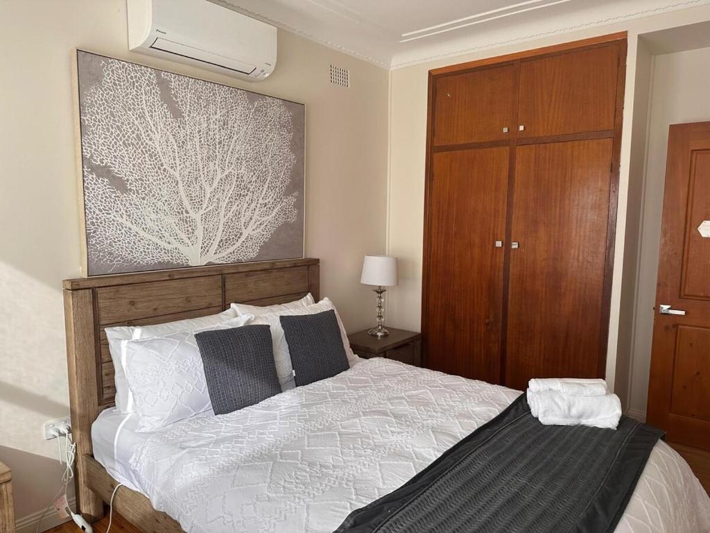Un dormitorio con una cama grande y un armario de madera. en Spacious 4BR Home Walk to Wollongong Uni, en Keiraville