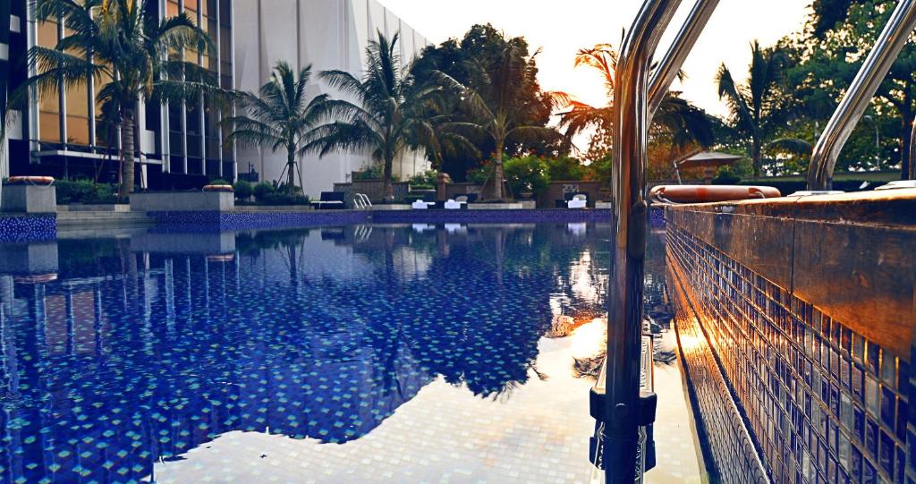 une piscine bordée de palmiers et un bâtiment dans l'établissement Fleuve Congo Hotel By Blazon Hotels, à Kinshasa