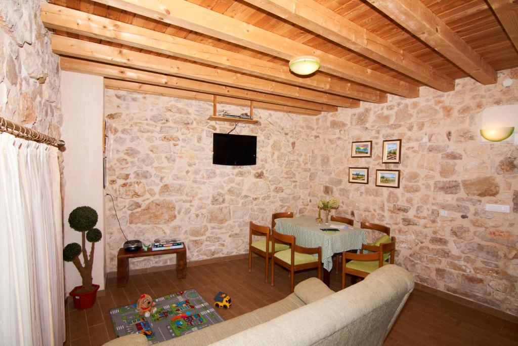 Dalmatian Stone House في كرابانج: غرفة معيشة مع طاولة وتلفزيون على جدار حجري