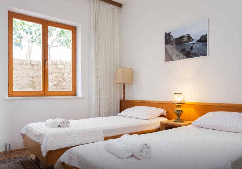a hotel room with two beds and a window at Apartment and Rooms Villa Marijo in Dubrovnik