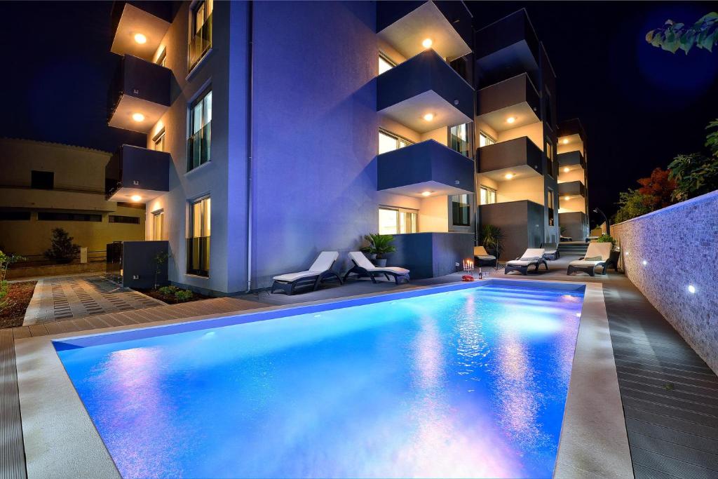 een zwembad voor een gebouw 's nachts bij Apartments Sun Resort Nikolina in Bibinje