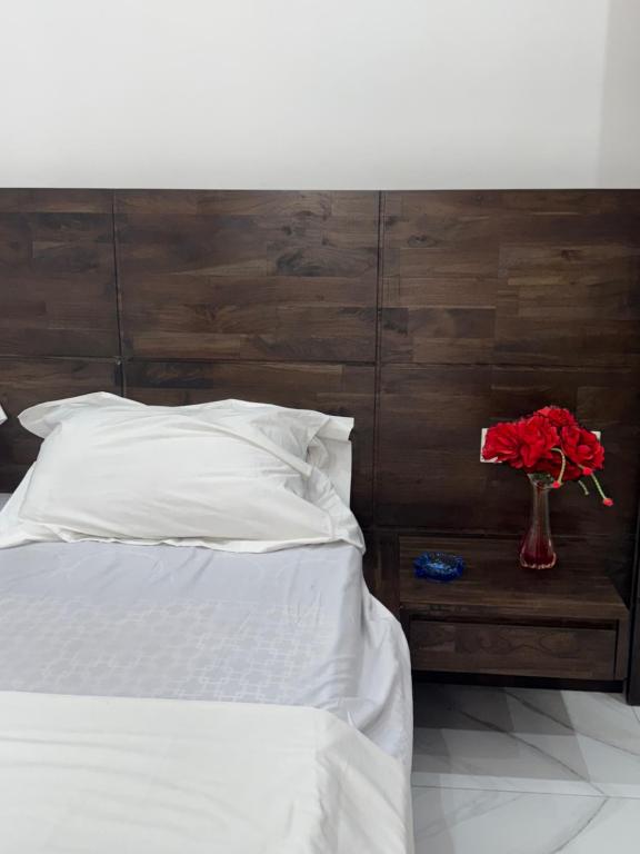 a bed with a vase of red flowers on a table at Résidence Fagnon in Cotonou