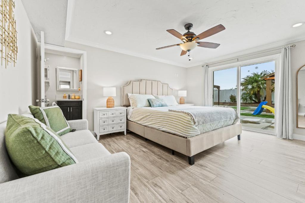 a bedroom with a bed and a couch and a ceiling fan at Peaceful Home Near Beach & Disneyland in Huntington Beach