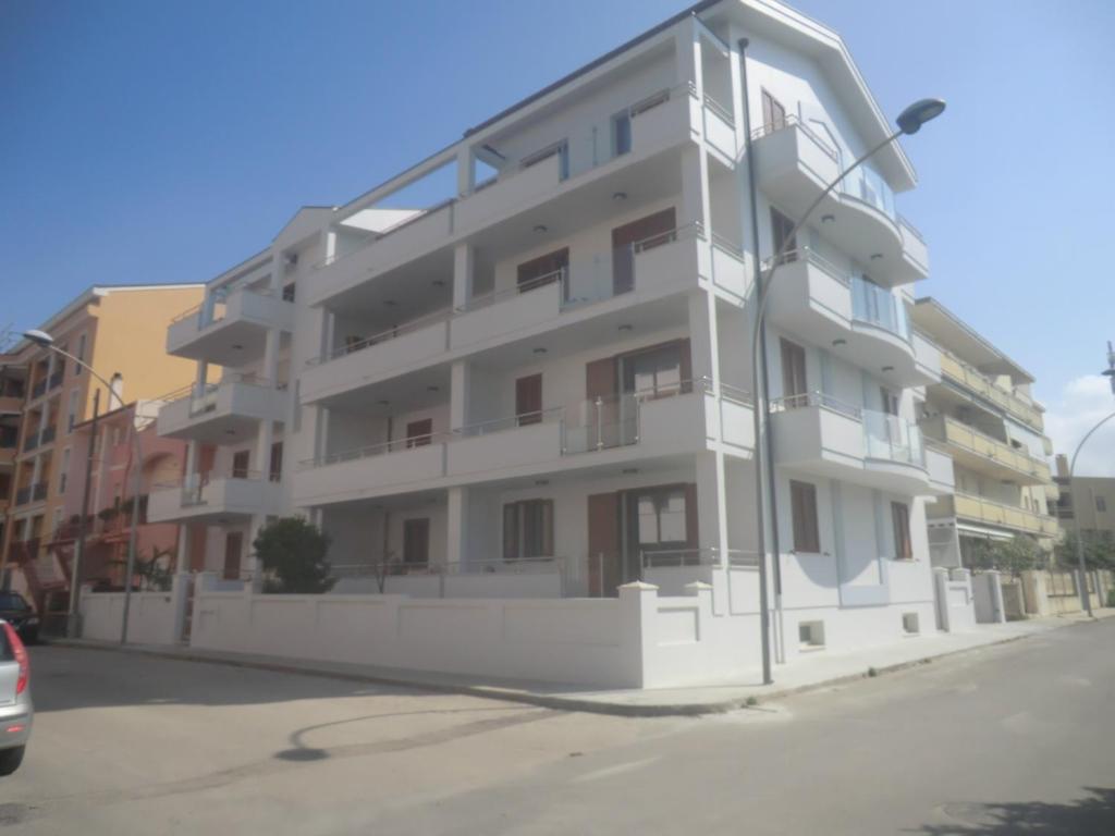 un condominio bianco sul lato di una strada di Alkira Lodge ad Alghero