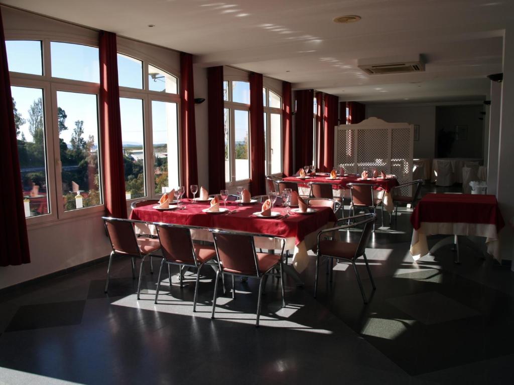 a dining room with red tables and chairs and windows at Hotel San Jorge in Alcalá de los Gazules