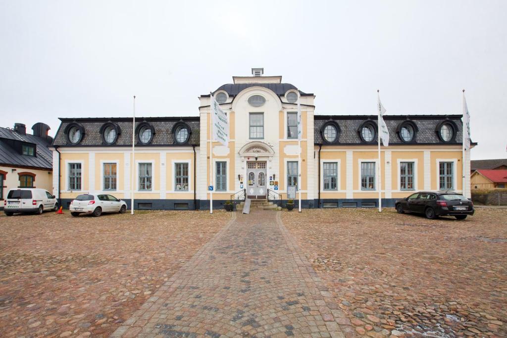 ein großes Gebäude mit davor geparkt in der Unterkunft Sjöbo Gästgifvaregård in Sjöbo