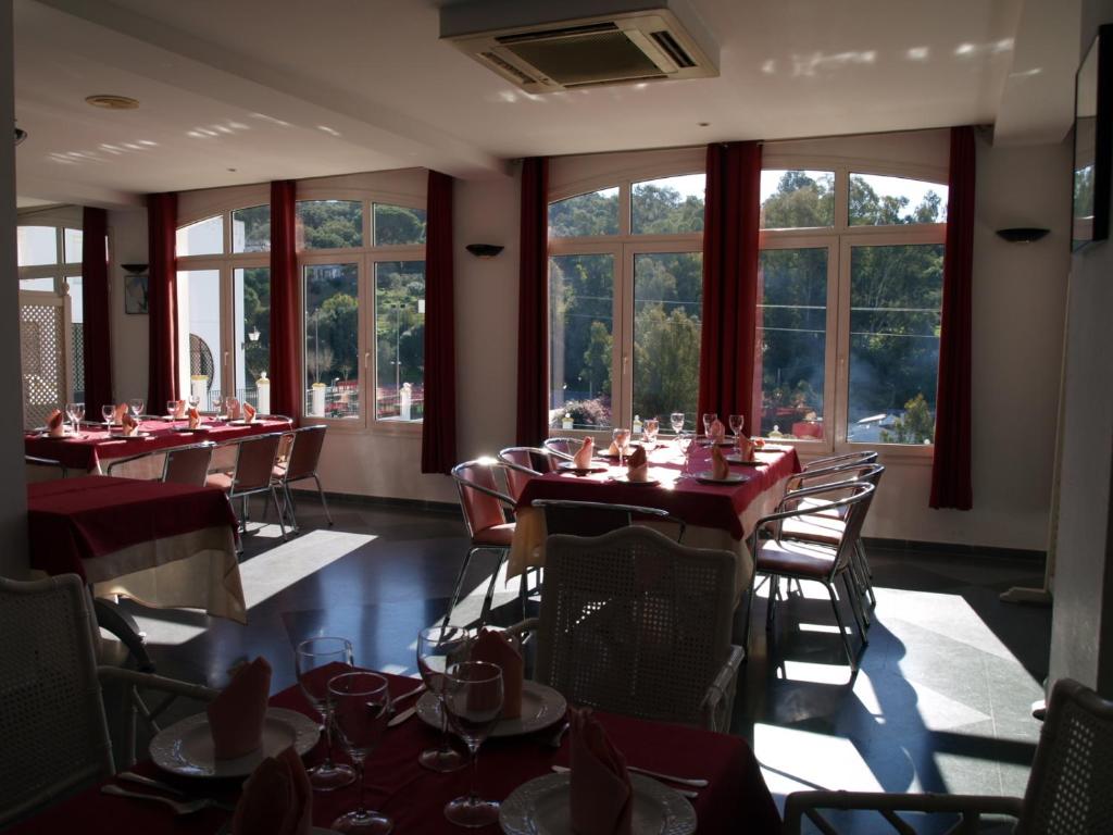 a dining room with tables and chairs and windows at Hotel San Jorge in Alcalá de los Gazules