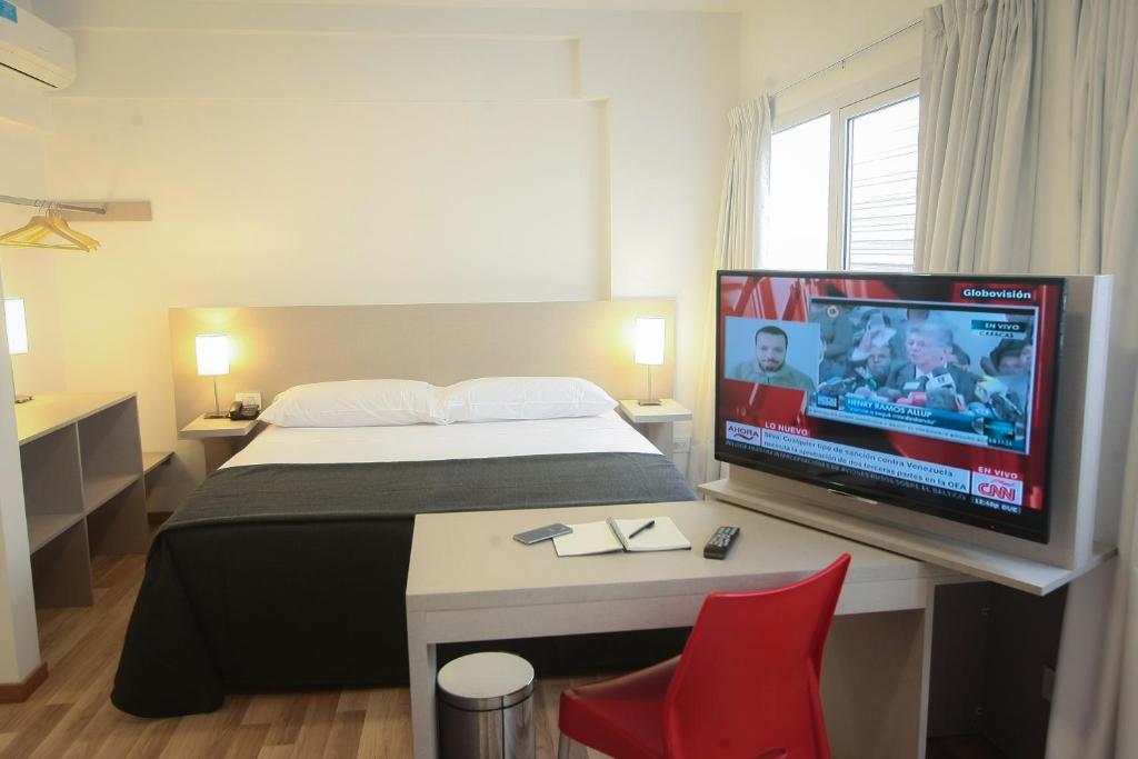 Habitación de hotel con cama y TV de pantalla plana. en Buen Pastor Capuchinos en Córdoba