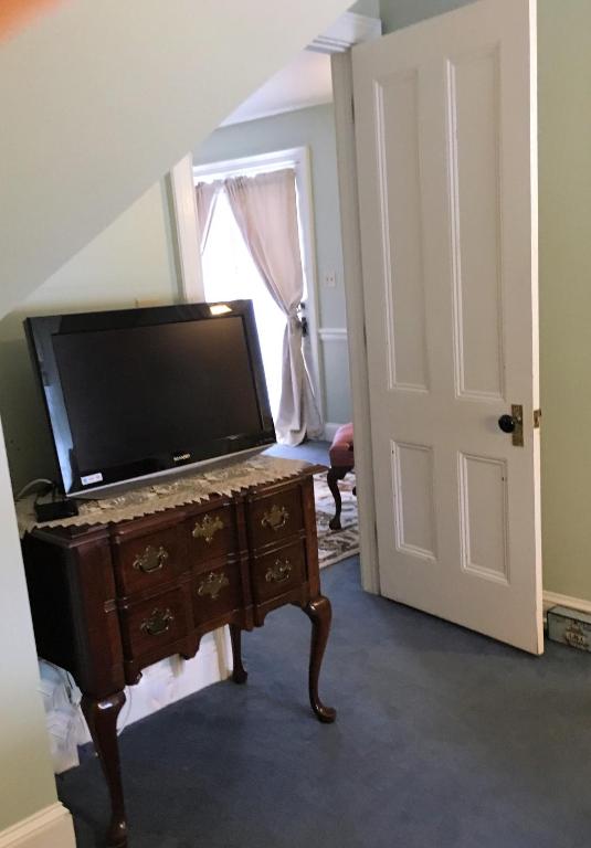 aoyer with a tv on a dresser and a door at Parsonage Inn Bed and Breakfast in Saint Michaels