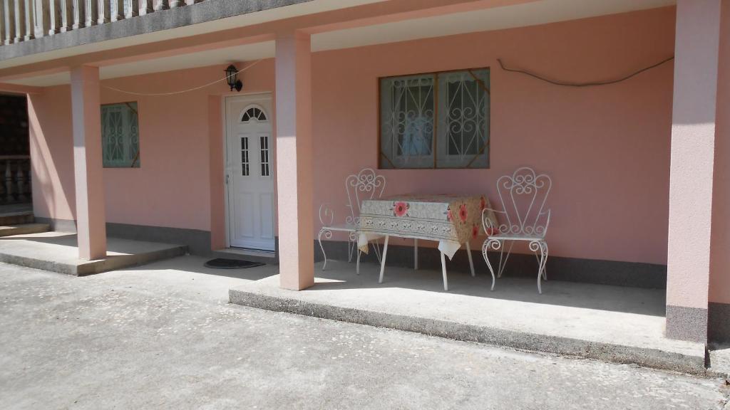 a pink house with two chairs and a door at Apartment and Rooms Novka in Kotor