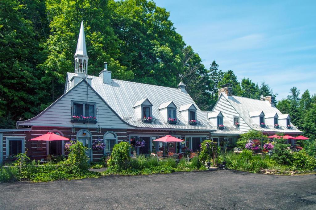 una iglesia con sombrillas rojas delante de ella en Le Petit Clocher Gite Touristique B & B en Saint-Sauveur-des-Monts