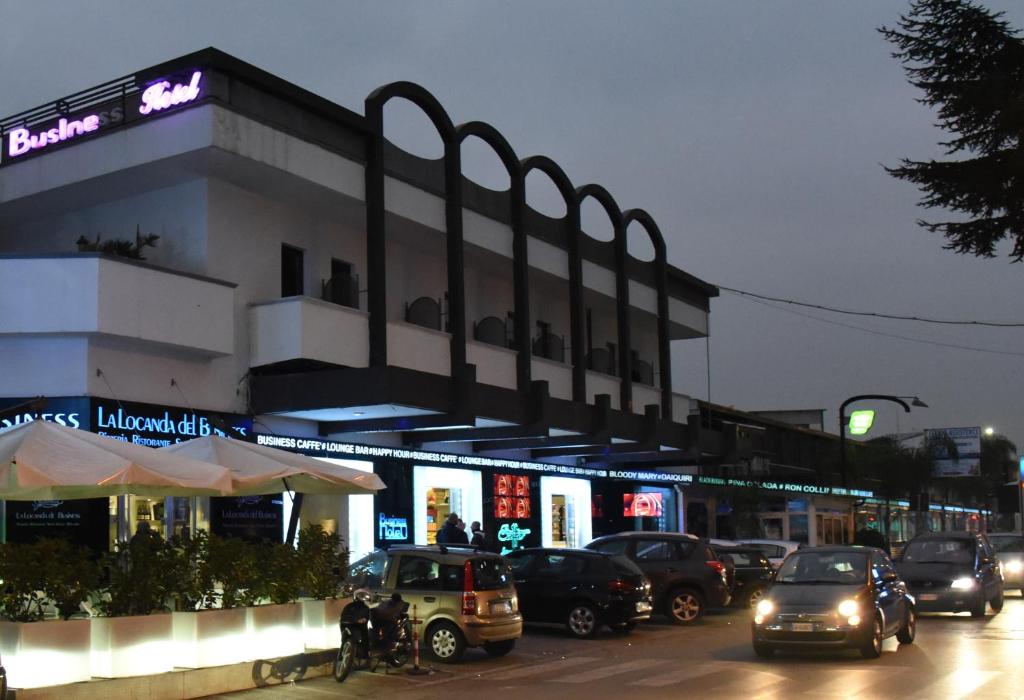 een gebouw met auto's in een stadsstraat 's nachts bij Business Hotel in Casoria