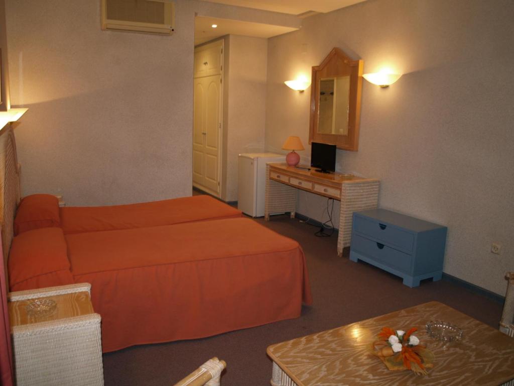 a hotel room with a bed and a desk and a table at Hotel San Jorge in Alcalá de los Gazules