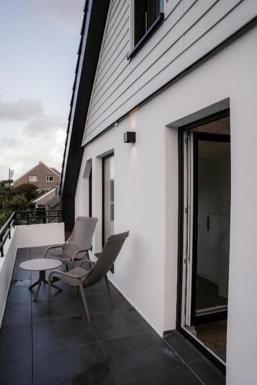 诺德奈EMS 6- Norderney的建筑物上的带椅子和桌子的阳台