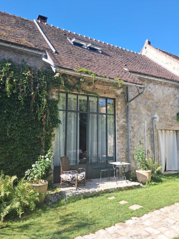 a patio of a house with a chair and a table at Ikigai Fontainebleau - Cottage in Villiers-sous-Grez