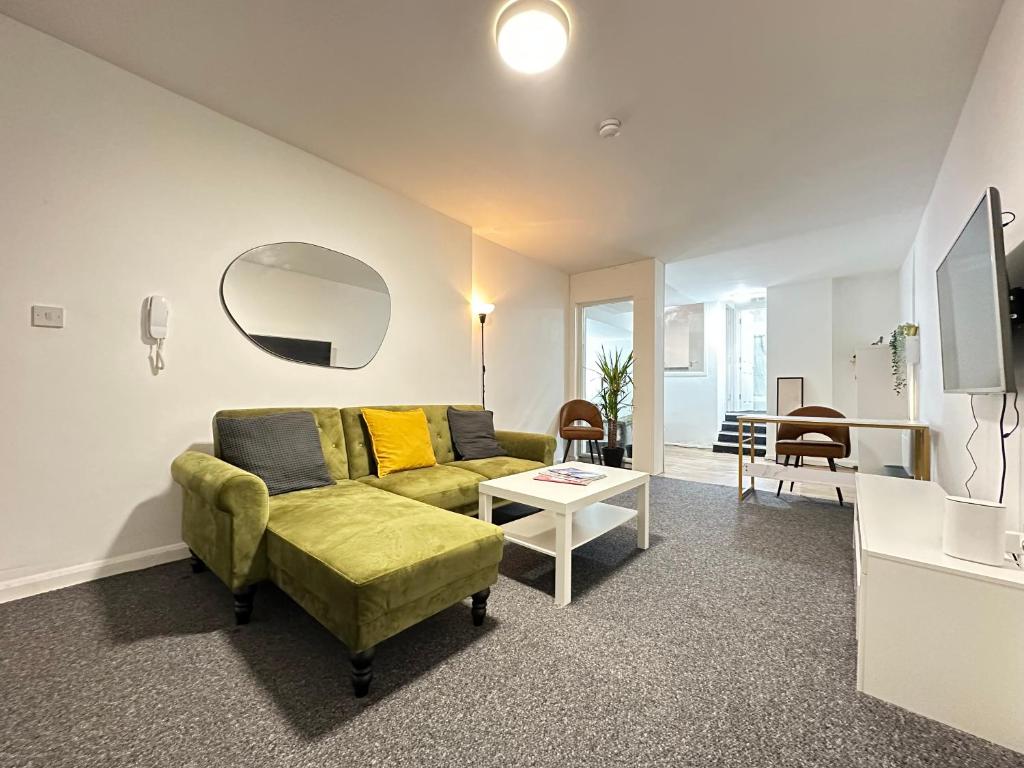a living room with a green couch and a table at The Bath Street Retreat in Ilkeston