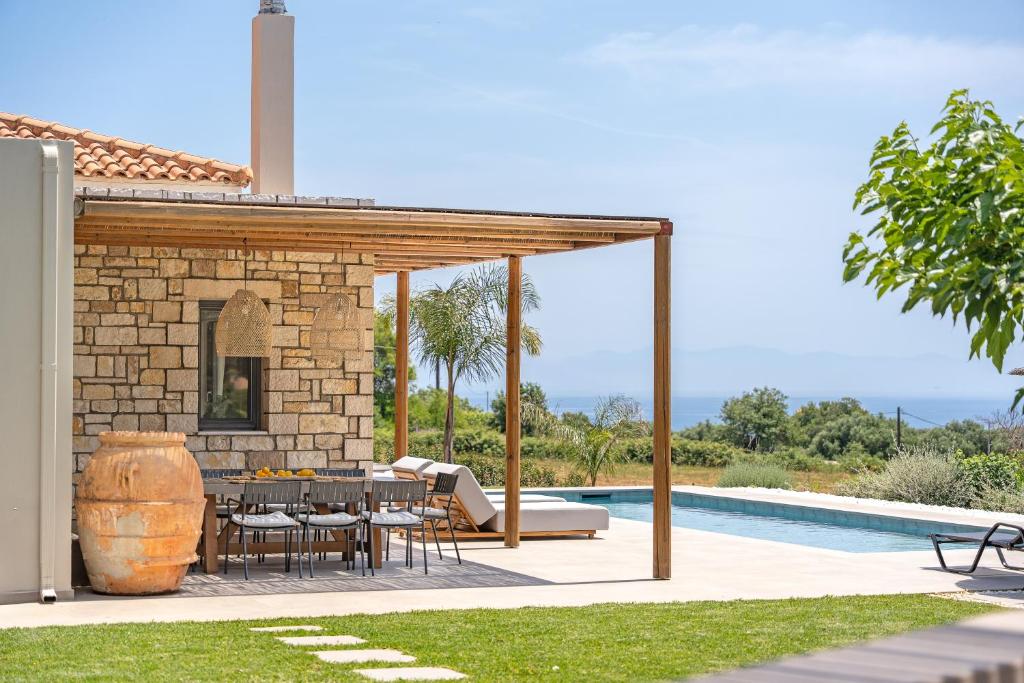 a patio with a table and a fireplace next to a pool at Alberi - Izla Homes in Skala Kefalonias