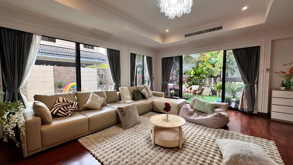 a living room with a couch and large windows at Thonglor 25 Noble House in Bangkok
