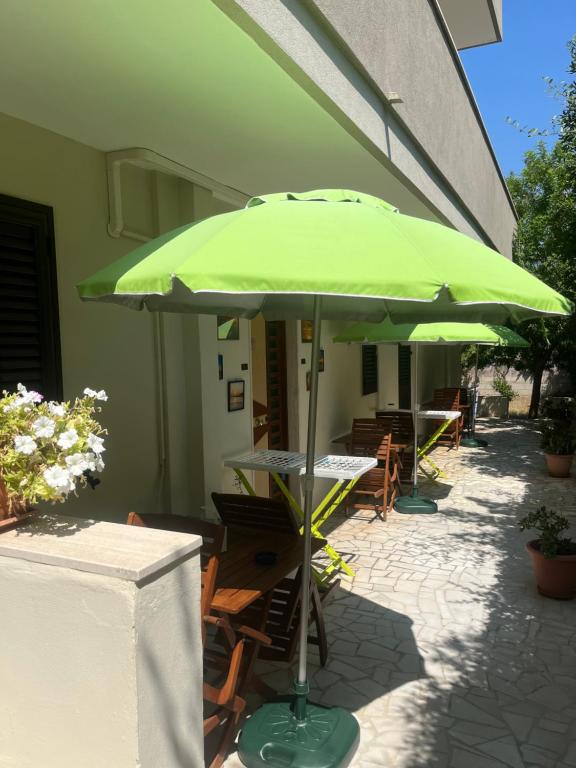 a green umbrella on a patio with tables and chairs at I Tramonti del Salento in Gallipoli
