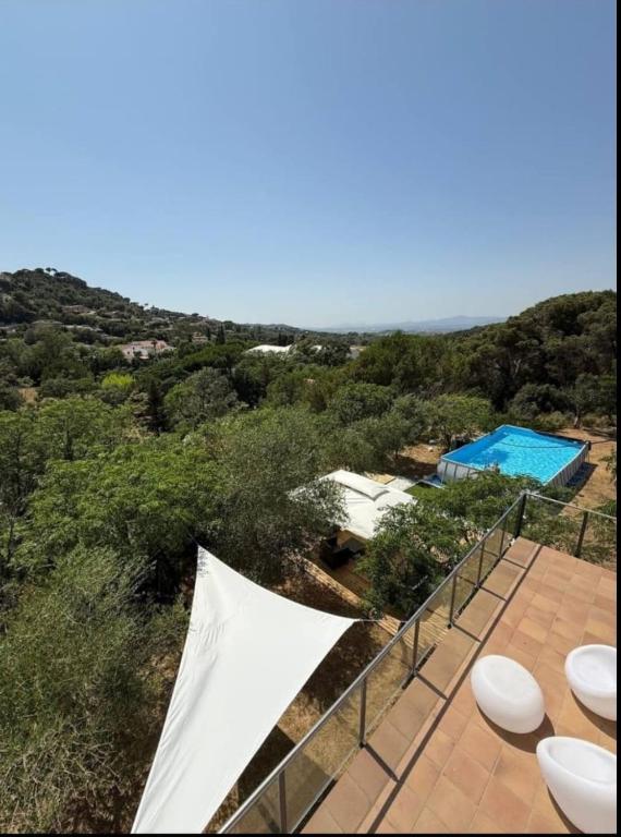 a balcony with white chairs and a swimming pool at Large house surrounded by nature in Vilanova de la Roca