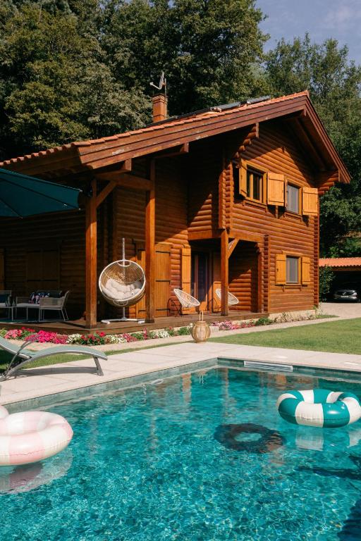 a log cabin with a swimming pool in front of it at Gerês Nature House Piscina Privada Aquecida 8 Pessoas in Campo do Gerês
