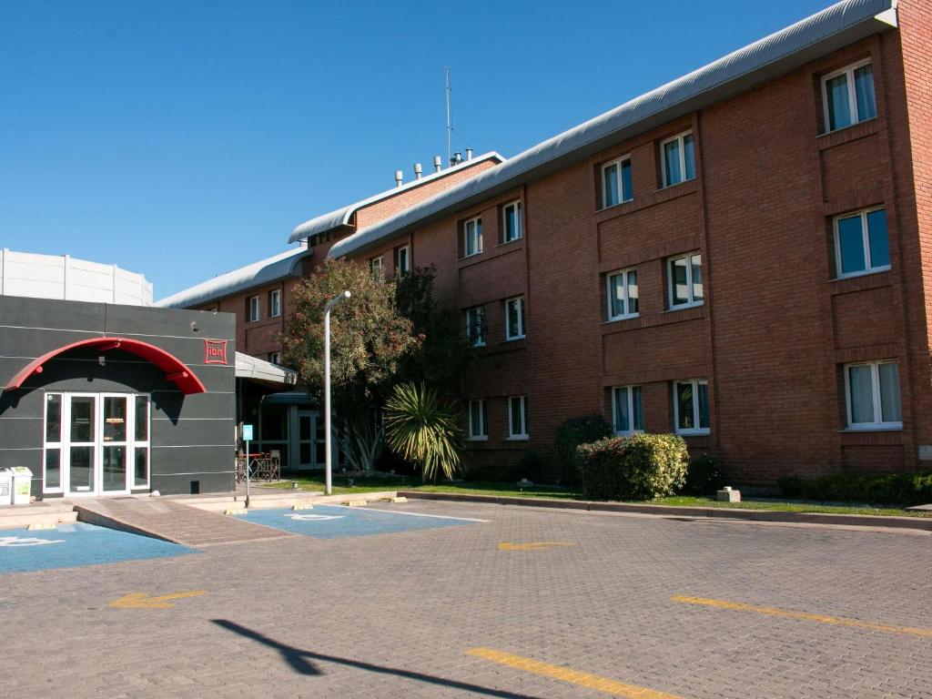 un gran edificio de ladrillo rojo con aparcamiento en ibis Mendoza, en Mendoza