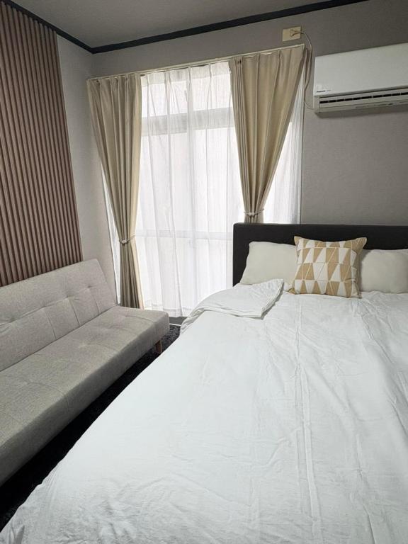 a bedroom with a large white bed and a window at 若葉コーポ103 in Fukuoka