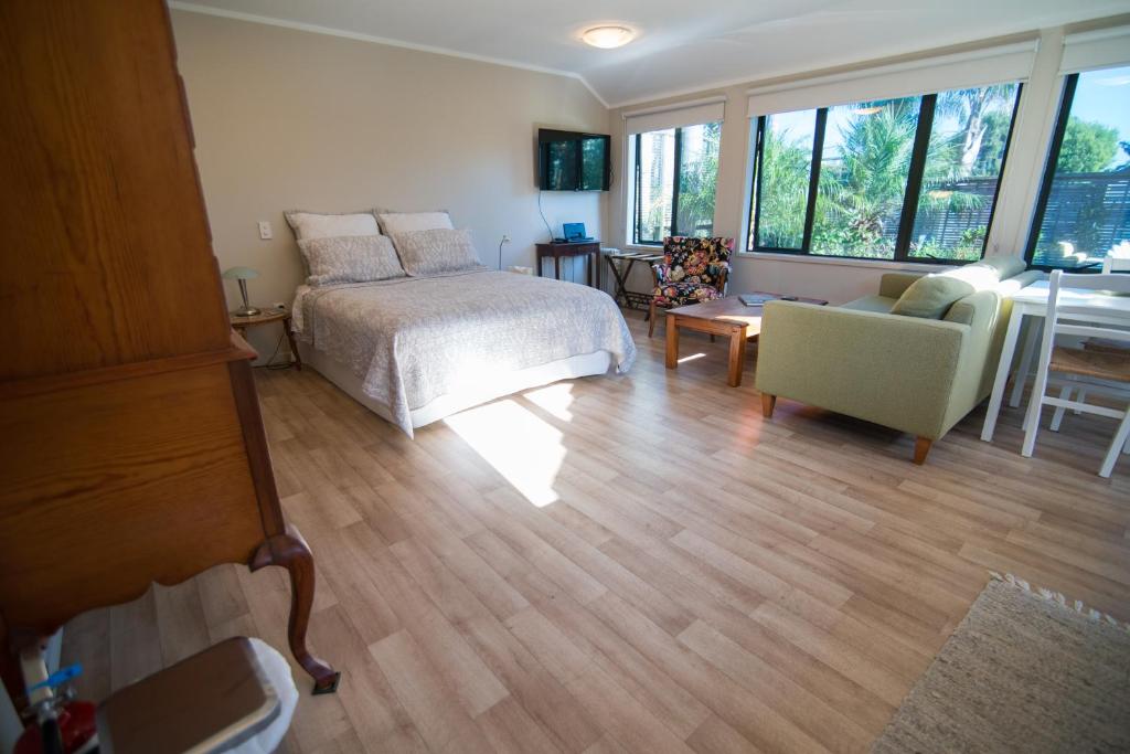 sypialnia z łóżkiem, kanapą i oknami w obiekcie Terry and Cindy's Bed and Breakfast w Auckland