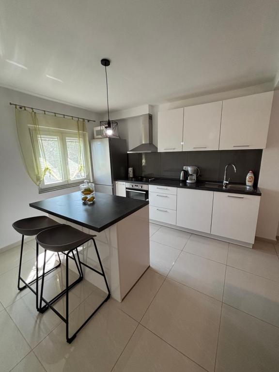 a kitchen with white cabinets and a black counter top at NEW Apartment Ema II in Vrh