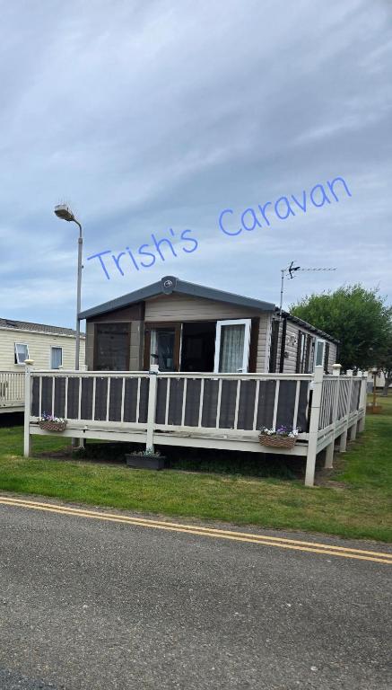 a house with a white fence and a sign on it at Trish's Caravan Coop 144 in Kinmel Bay