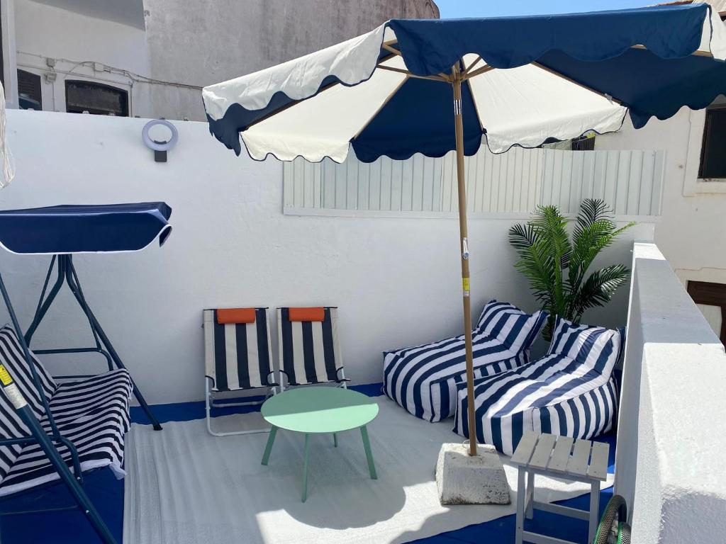un patio avec deux chaises, une table et un parasol dans l'établissement Blue Beach Home with Terrace, à Albufeira