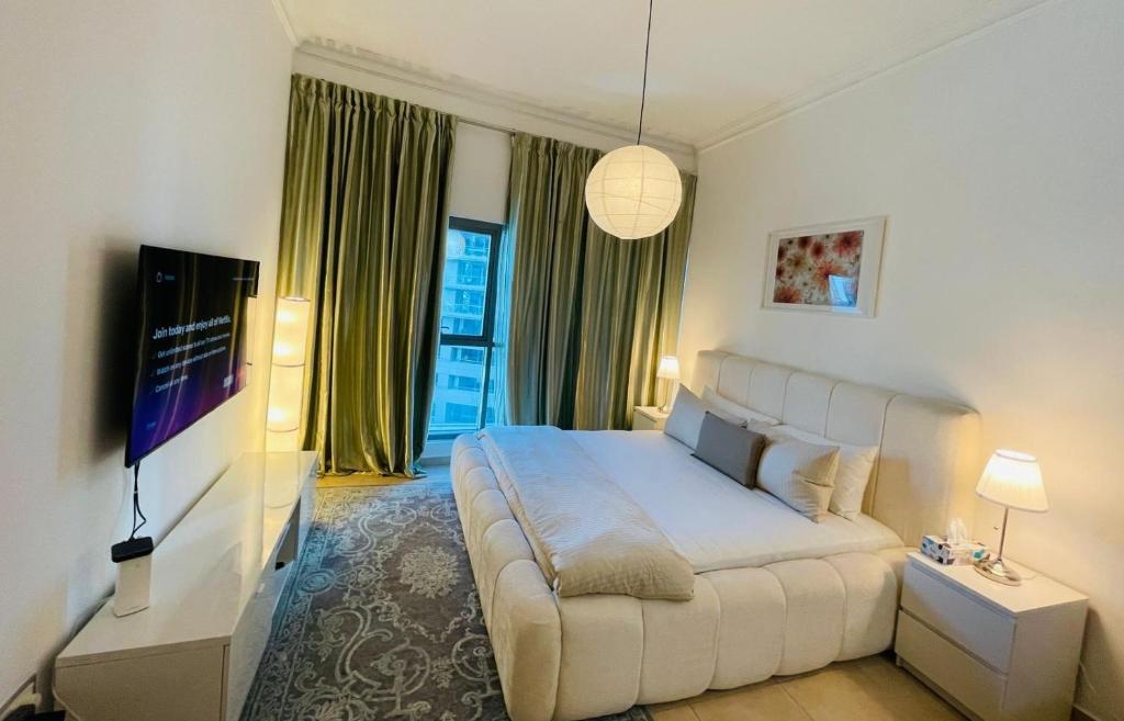 a bedroom with a large white bed and a tv at Big Studio Apartment in Dubai Marina Walking to JBR Beach, Cruise and DMCC Metro in Dubai