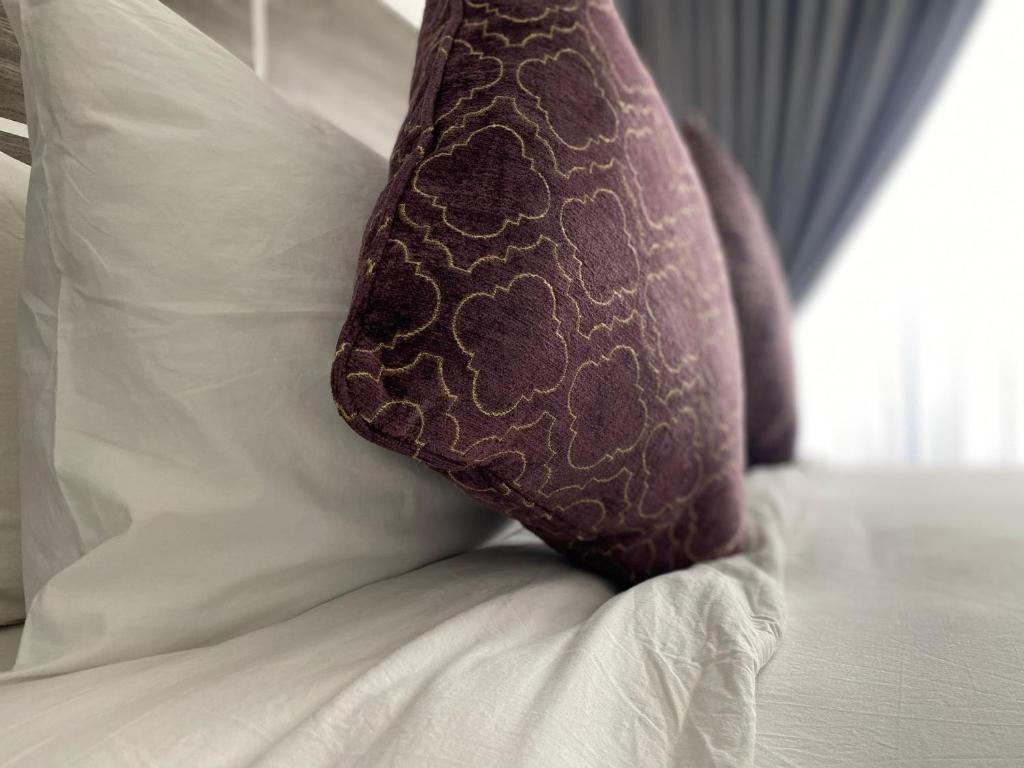 uma almofada castanha sentada em cima de uma cama em Styluxe Studio Apartment em Accra