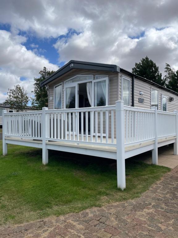a mobile home with a white railing and a porch at Happy Holiday Seton Sands in Port Seton