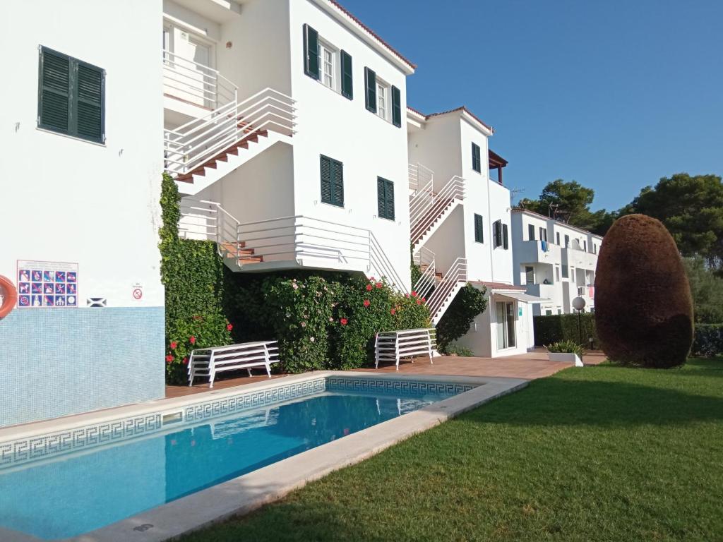una villa con piscina frente a un edificio en Apartamentos Piscis, en Cala Blanca