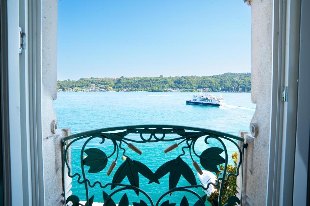 a window with a view of the water and a boat at Victoria Palace in Salò