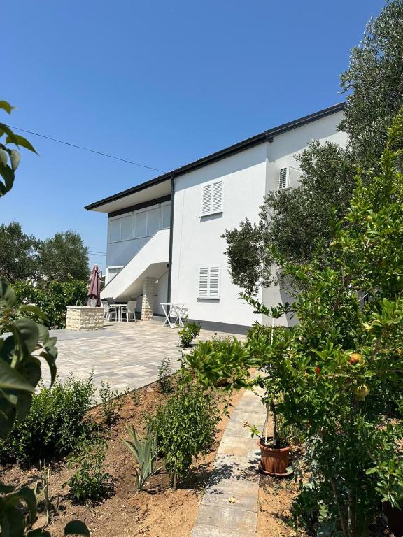 a white building with a patio in front of it at Apartment Oblak in Vrsi
